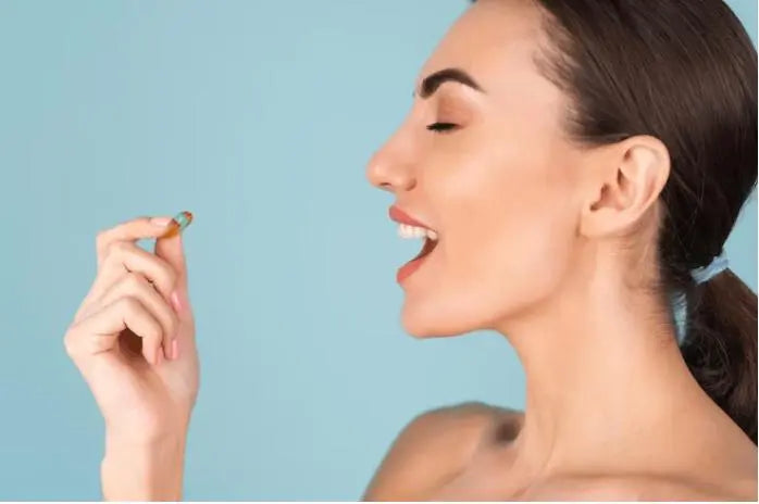 Mulher segurando cápsula de antioxidante, destacando benefícios à saúde.