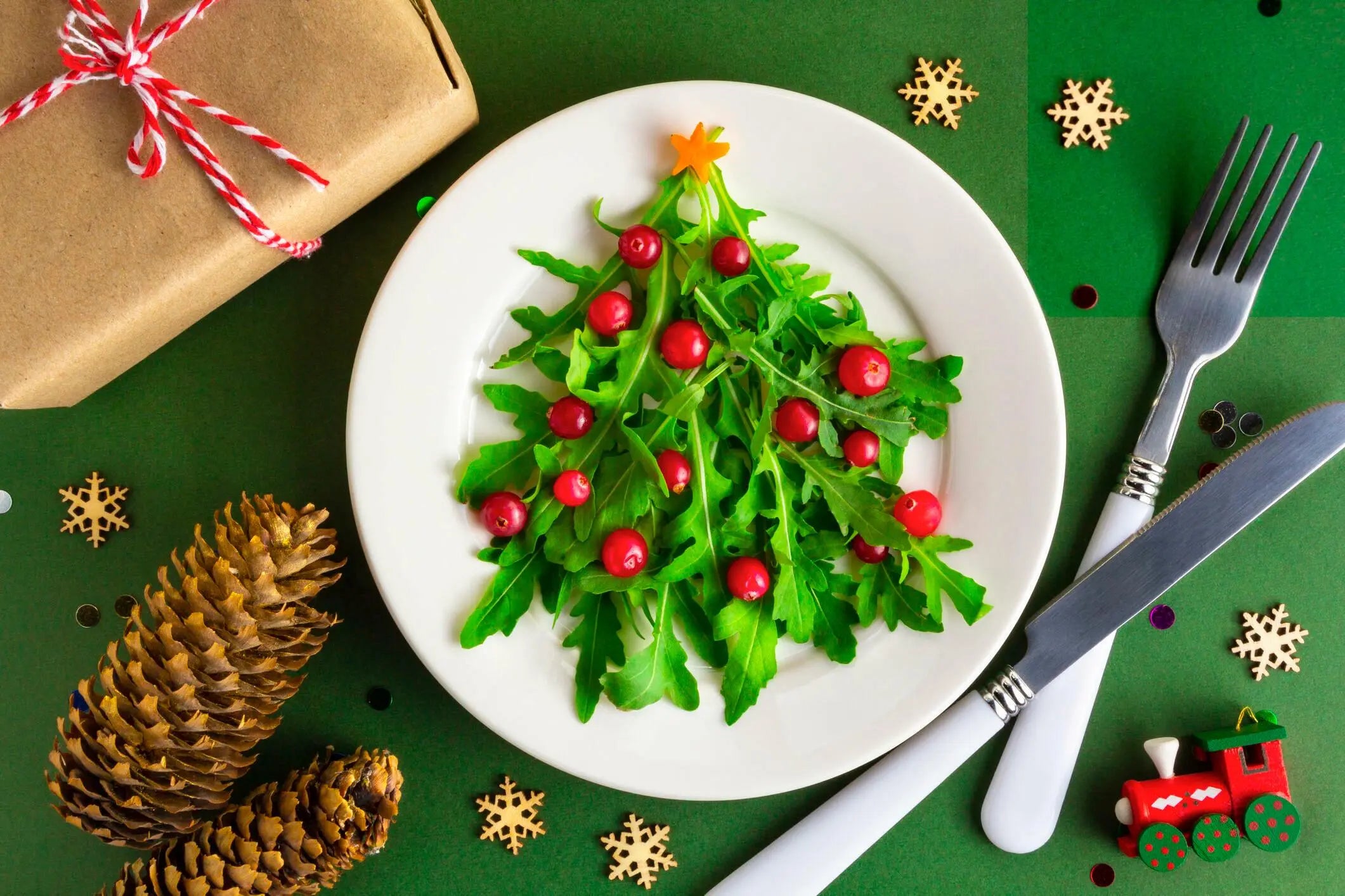 Árvore de Natal feita com rúcula e cranberries em prato branco, decoração natalina.