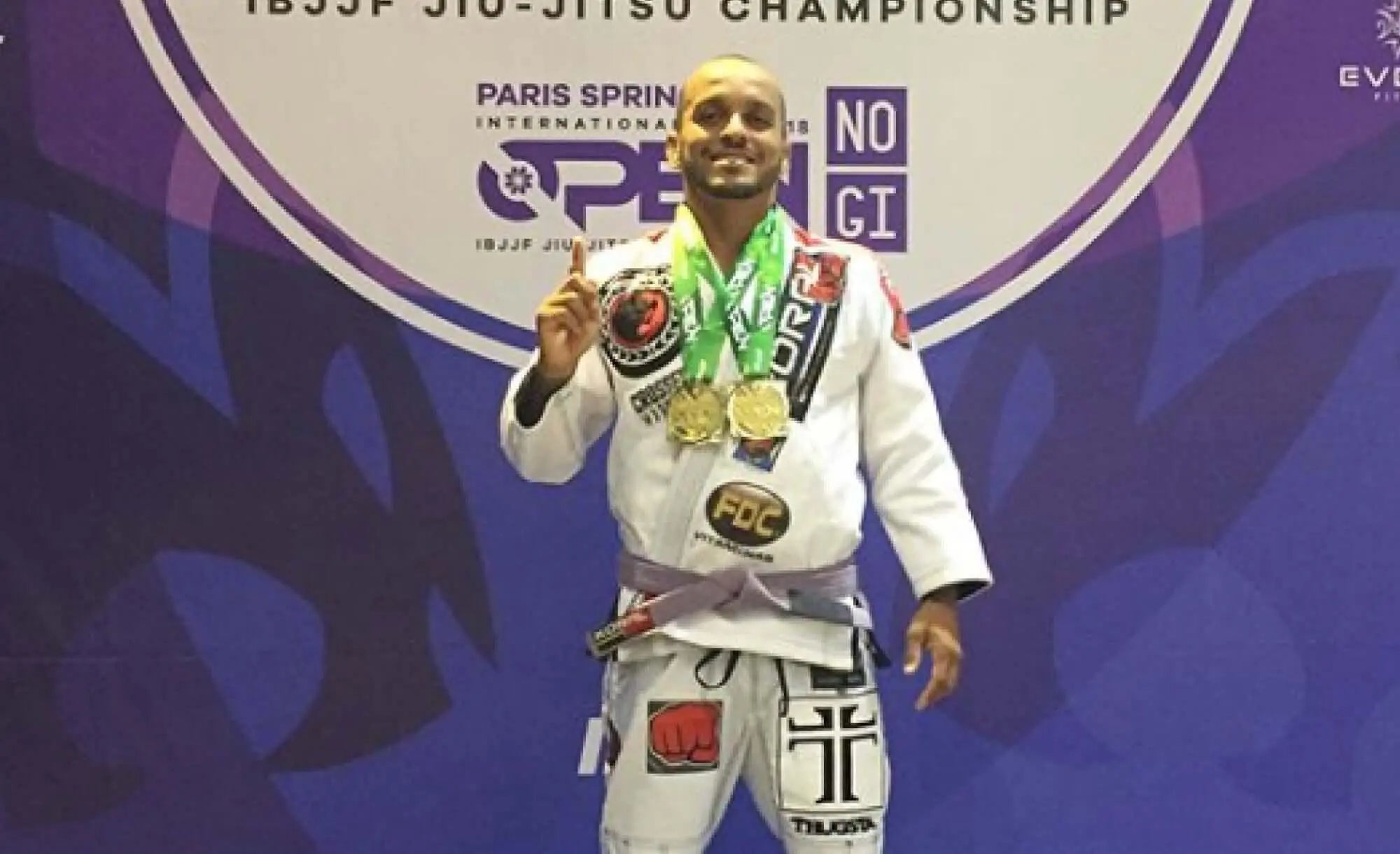 Texto alternativo:Alexandre Amparo, atleta de Jiu-Jitsu do time FDC, exibindo medalhas em campeonato.
