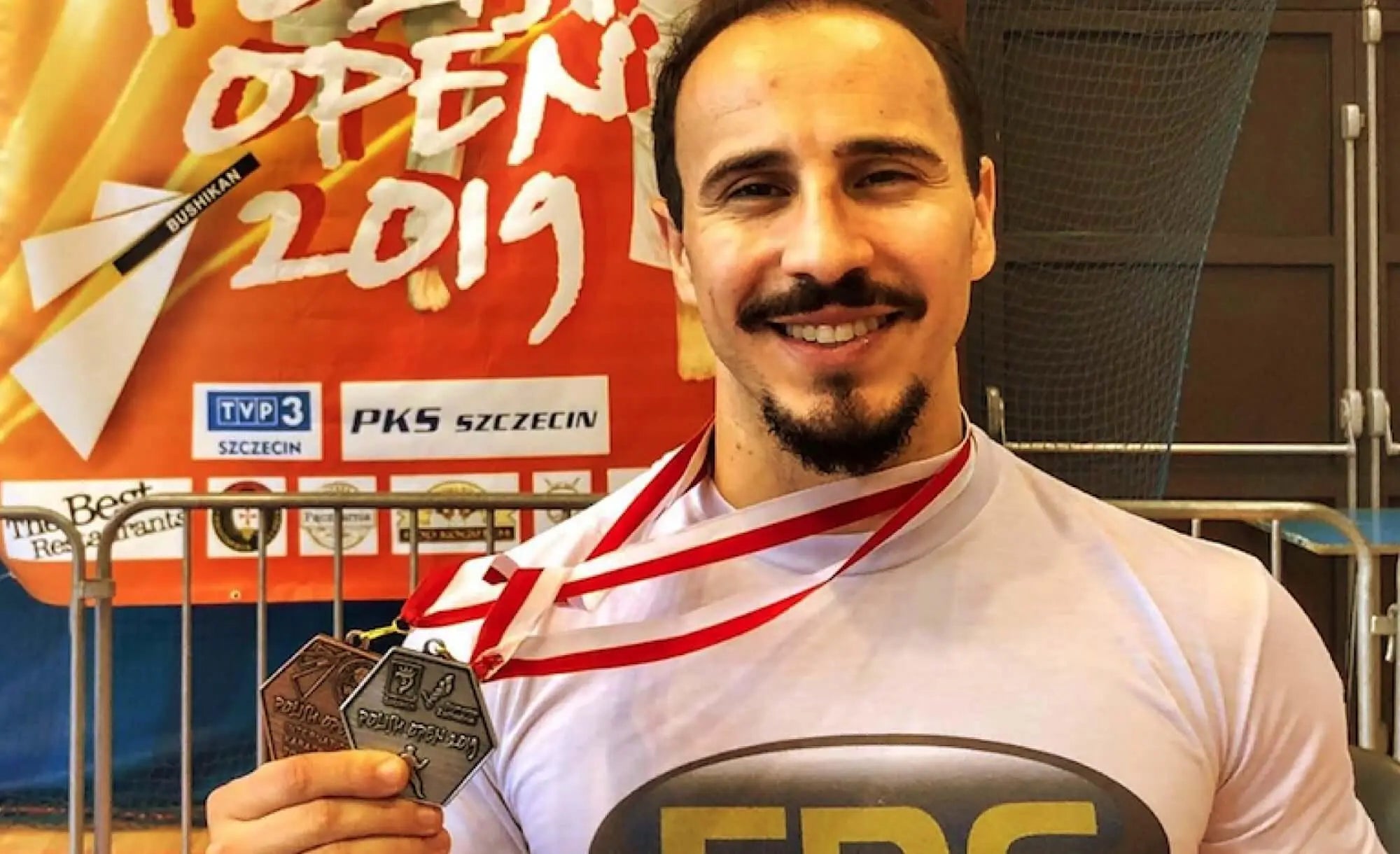 Atleta Sttenio Almeida sorrindo e exibindo medalhas conquistadas em competição de Karate.