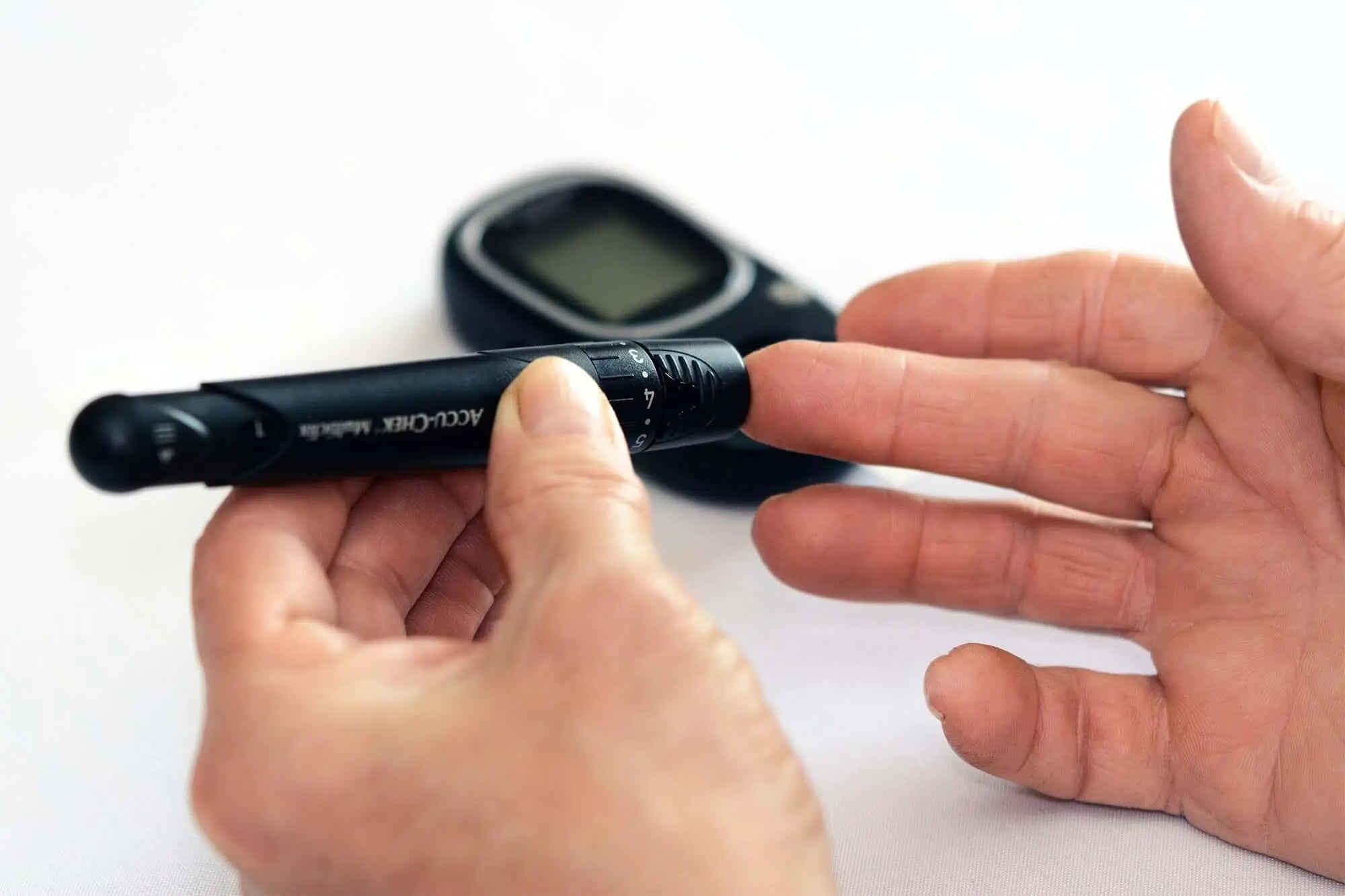 Pessoa medindo glicemia com glicosímetro, destacando controle do diabetes.