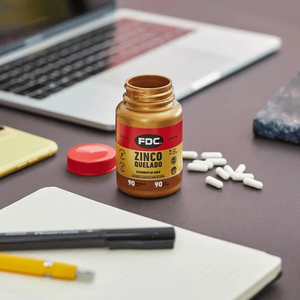 Texto alternativo:Suplemento de Zinco Quelado da FDC em destaque sobre mesa com cápsulas.