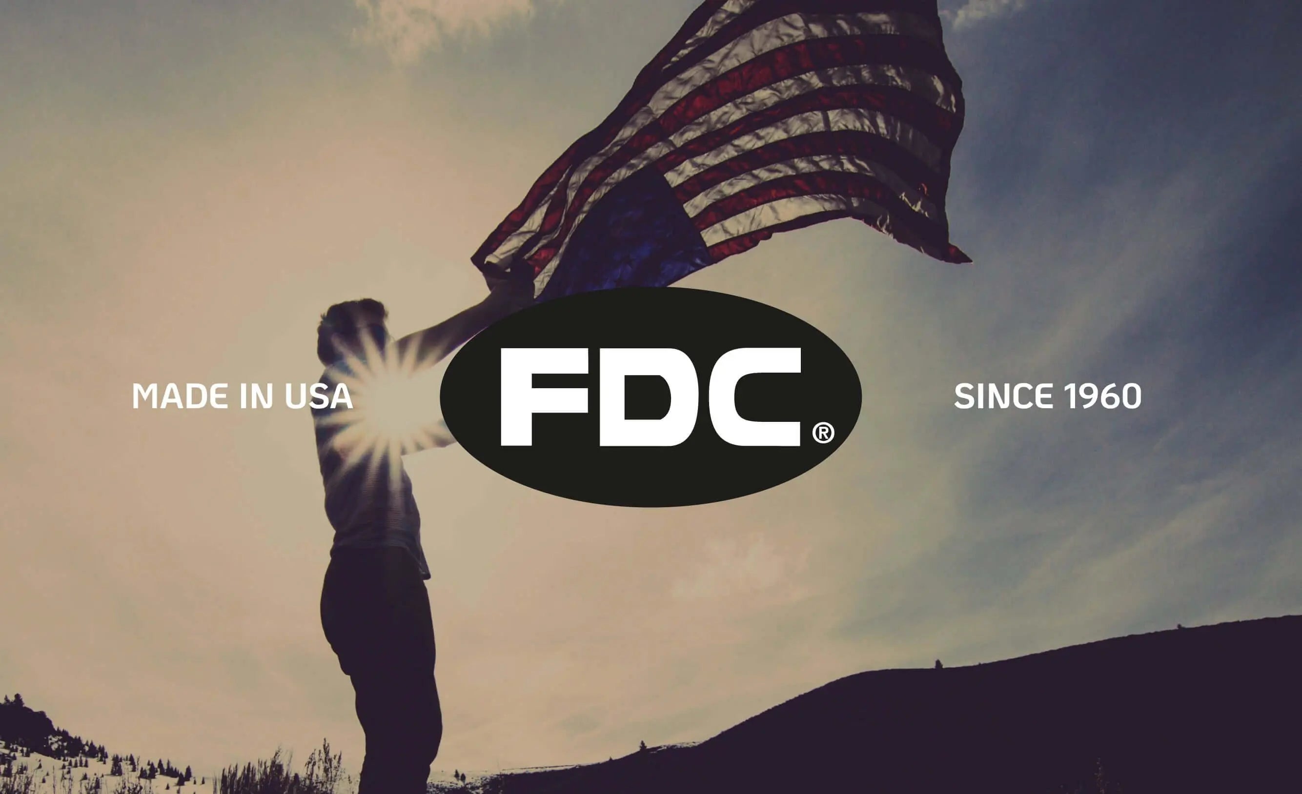 Homem segurando bandeira dos EUA ao pôr do sol com logotipo FDC ao centro.