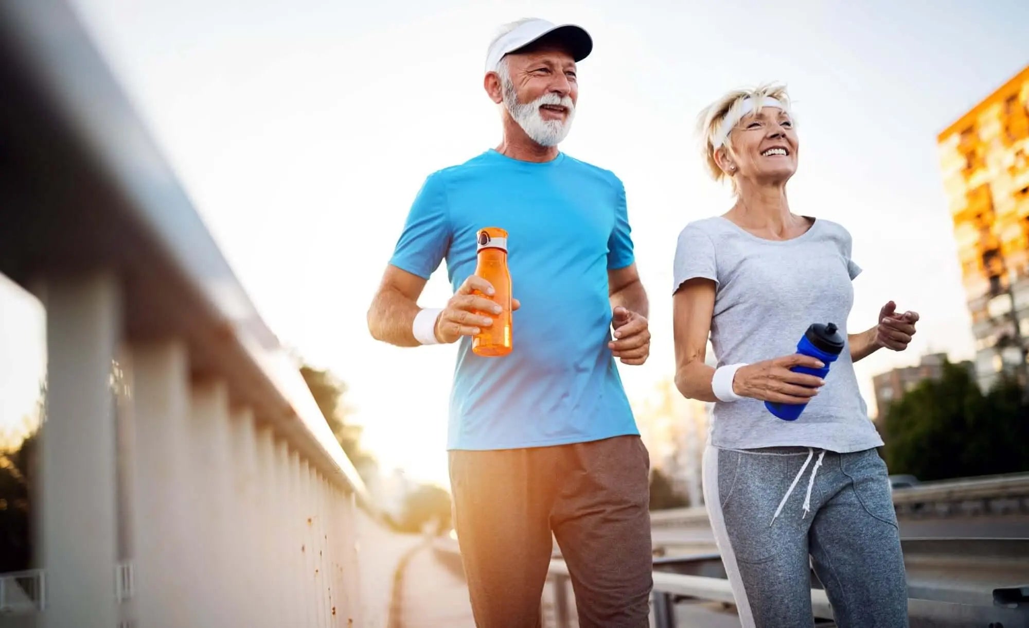 Casal idoso praticando corrida ao ar livre, promovendo saúde óssea.