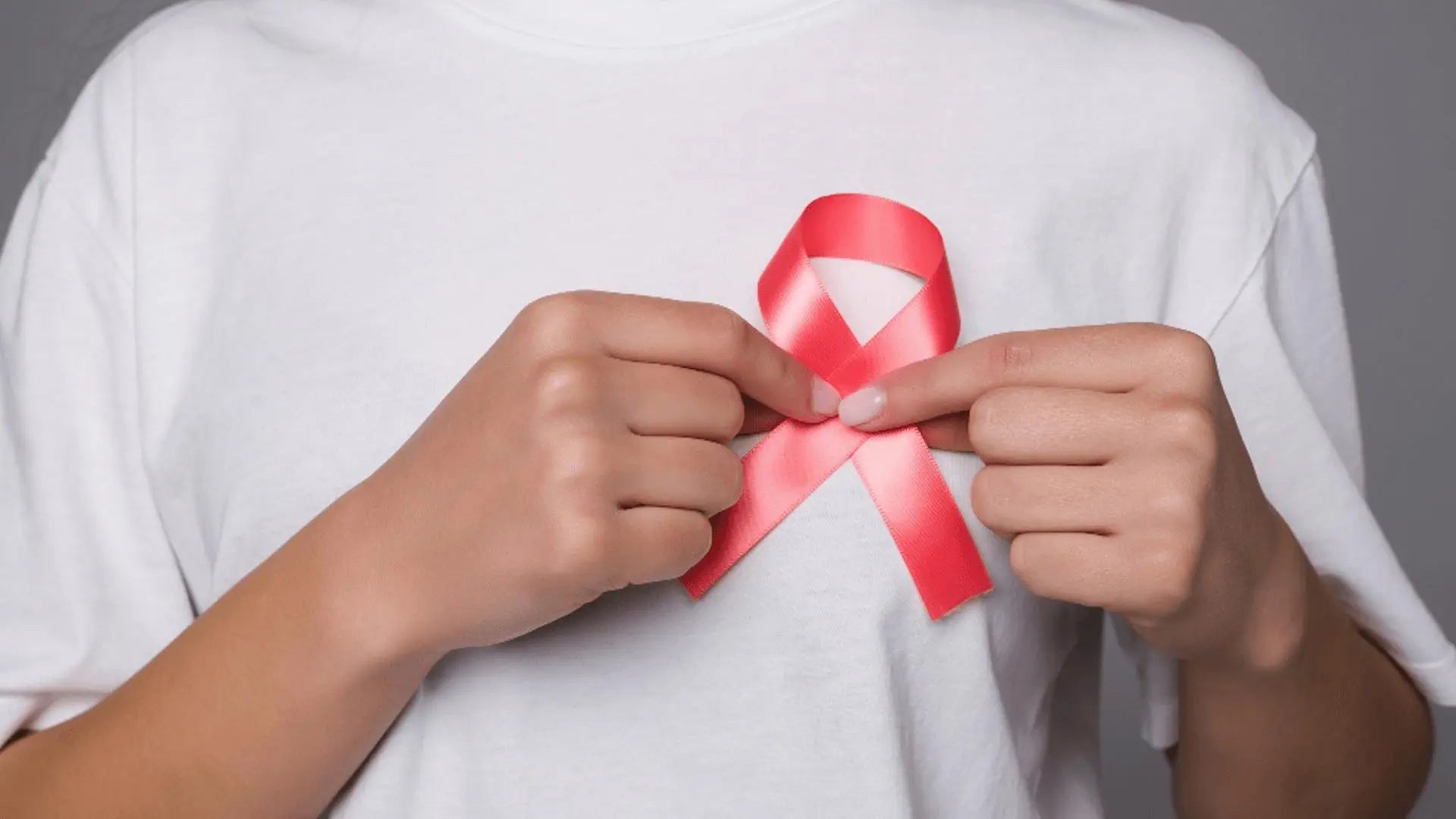 Pessoa segurando laço rosa, símbolo da conscientização sobre o câncer de mama.