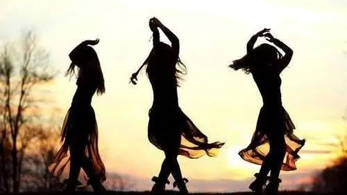 Texto alternativo:Silhuetas de três mulheres dançando ao pôr do sol, em movimento gracioso.