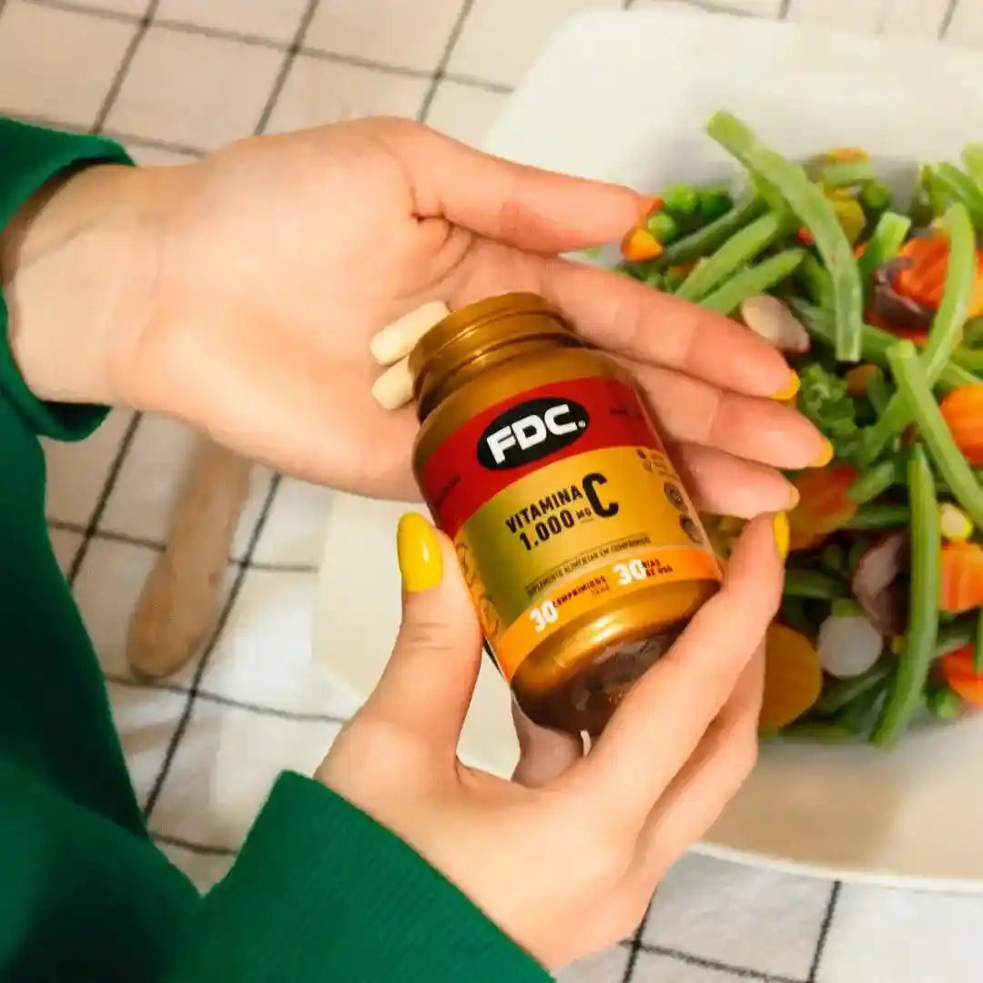 a woman is holding a bottle of vitamin c in front of a plate of vegetables