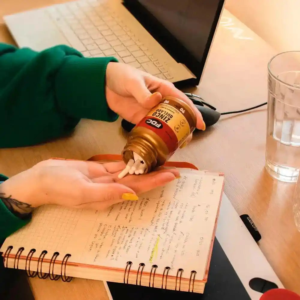 a person is holding a bottle and writing on a notebook