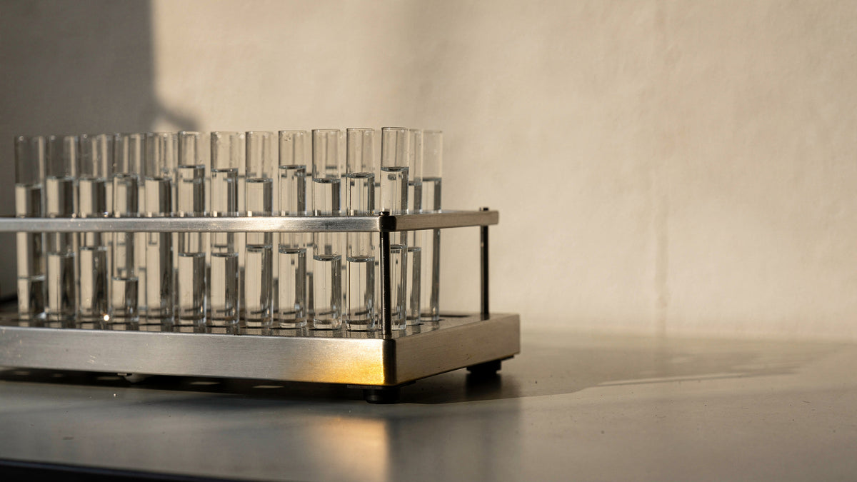 Instrumento analítico de laboratório em aço inox com rack de frascos de vidro sobre bancada