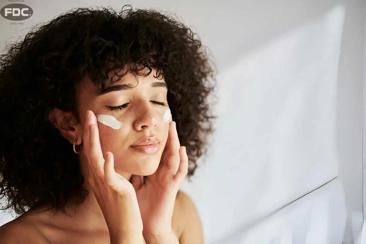Texto alternativo:Mulher aplicando creme hidratante no rosto para cuidados com a pele no inverno.