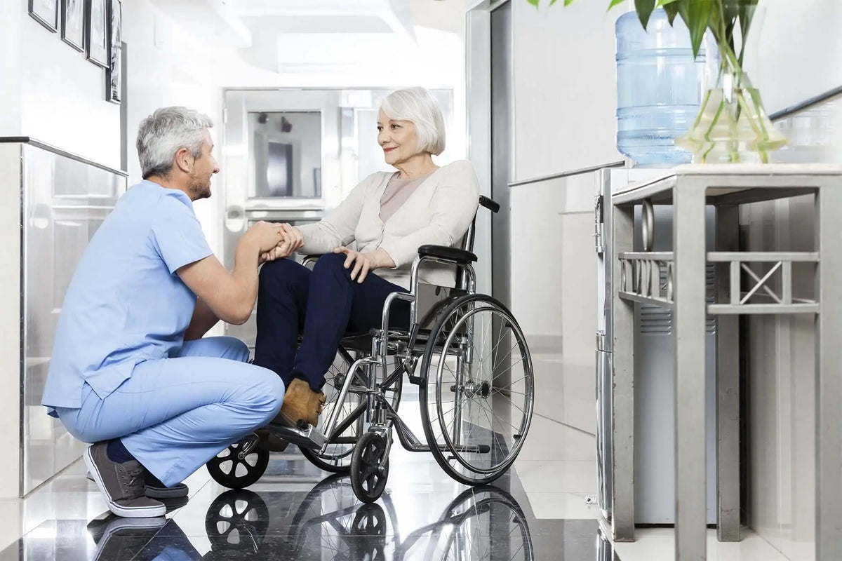 Profissional de saúde cuidando de idosa em cadeira de rodas em ambiente hospitalar.