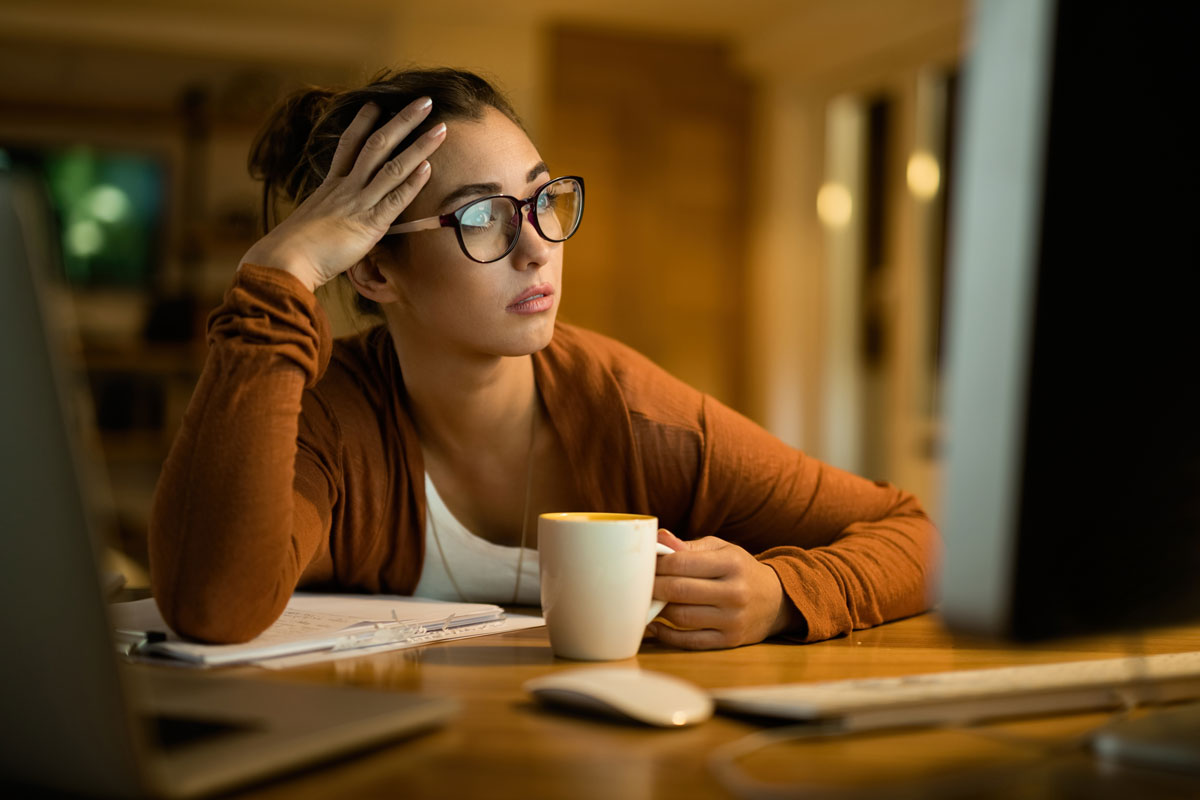 Texto alternativo:Mulher pensativa com xícara de café, refletindo sobre saúde mental e vitaminas B.