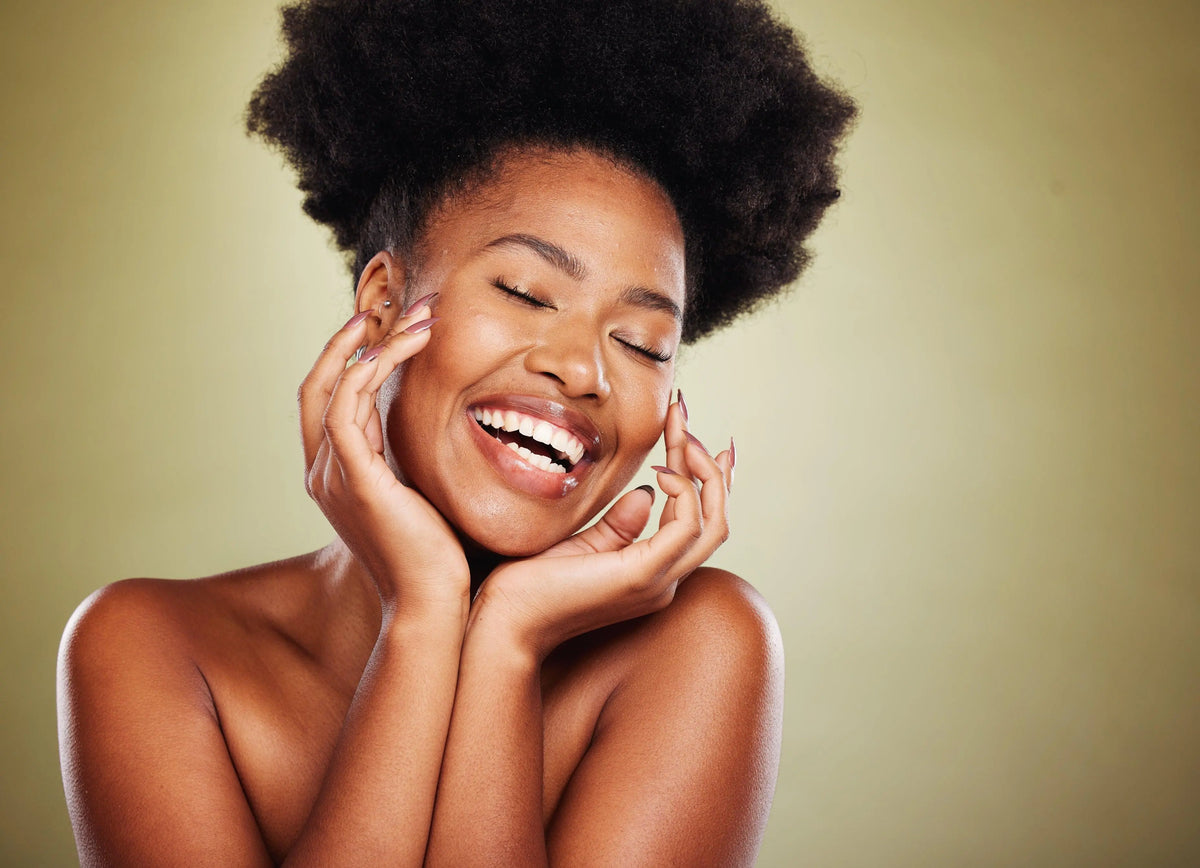 Mulher sorrindo com pele radiante, cabelo volumoso e unhas bem cuidadas.