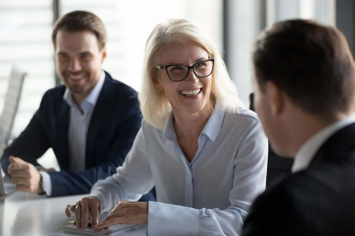 Texto alternativo:Profissionais sorrindo em reunião, simbolizando trabalho em equipe e comunicação.
